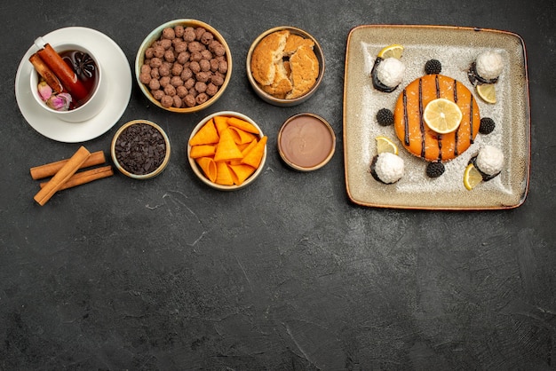 Vista dall'alto deliziosa piccola torta con una tazza di tè su sfondo scuro caramelle biscotto torta torta biscotto dolce