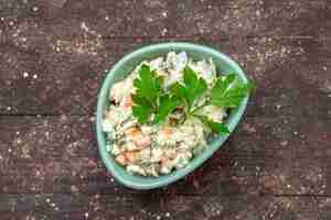 Foto gratuita vista dall'alto deliziosa insalata di maionese all'interno del piatto verde con verde sulla foto di spuntino del pasto del pasto dell'insalata dello scrittorio di legno marrone