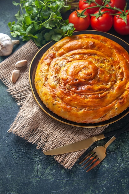 Top view of delicious meat pie with ingredients on dark surface