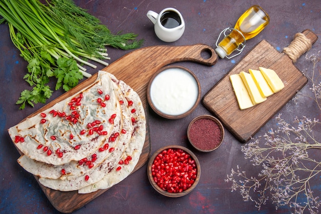 Top view delicious meat qutabs pitas with fresh red pomegranates on dark surface dough meal food pita