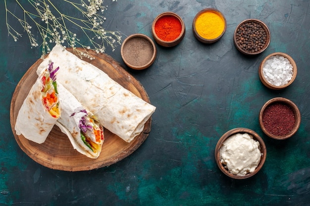 Vista dall'alto delizioso panino di carne fatto di carne alla griglia allo spiedo affettato con condimenti sulla scrivania blu hamburger pasto a base di carne pranzo panino