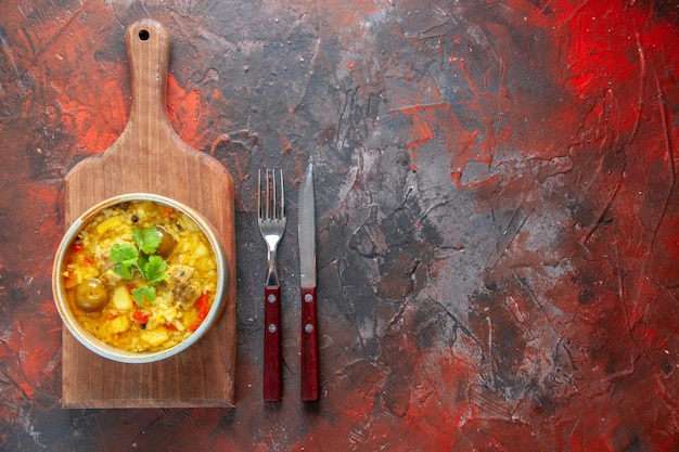 Вид сверху вкусный мясной суп внутри маленькой тарелки со столовыми приборами на темно-красном фоне овощная кулинария еда кухня еда блюдо мясо готовить ужин свободное место