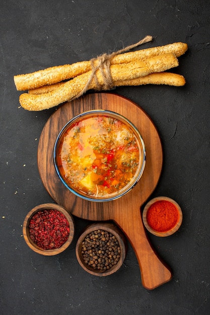 Top view delicious meat soup with bread and seasonings on dark-grey space