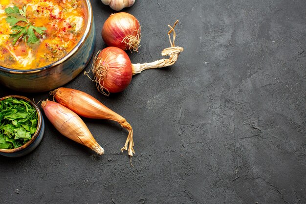 Вид сверху вкусного мясного супа с нарезанными овощами на сером пространстве