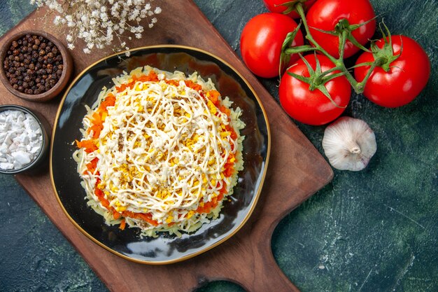 вид сверху вкусный салат из мимозы внутри тарелки с красными помидорами на темно-синем фоне