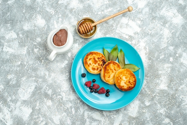 Foto gratuita muffin deliziosi vista dall'alto con frutti di bosco su sfondo chiaro