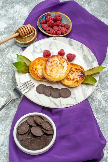 Top view delicious muffins with choco biscuits honey and raspberries on a light background
