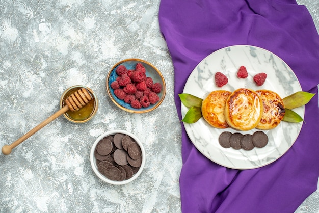 Free photo top view delicious muffins with choco biscuits and raspberries on light background