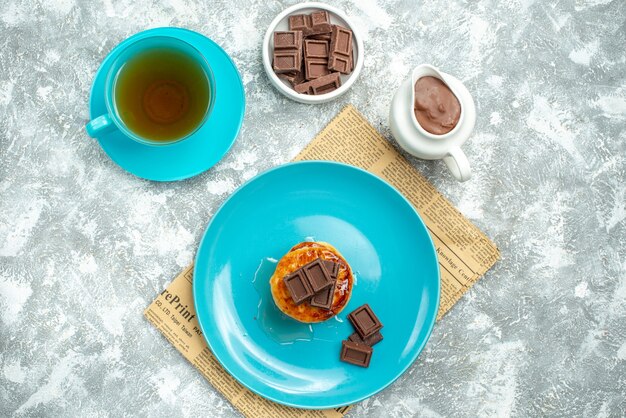 Top view delicious muffins with cup of tea and chocolate on light background