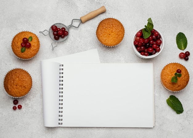 Top view of delicious muffins with notebook and berries