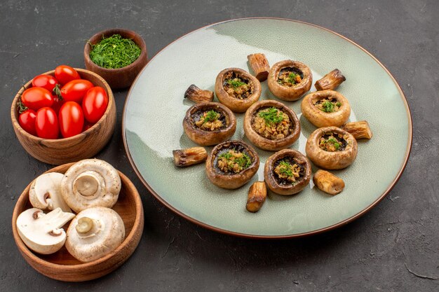 Вид сверху вкусной грибной еды со свежей зеленью и помидорами на темном полу блюдо ужин еда приготовление грибов