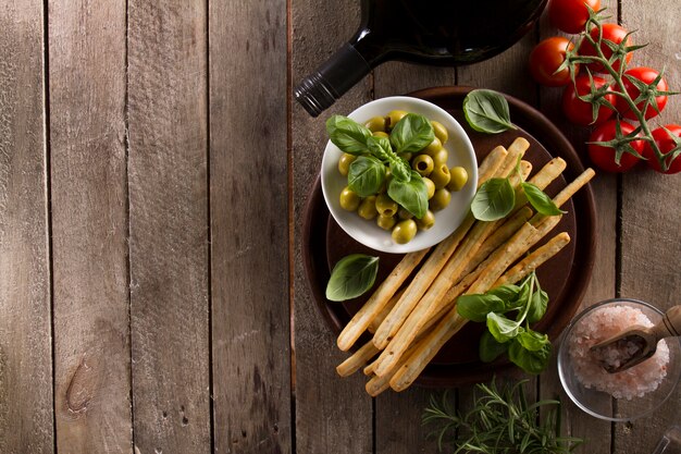 Top view of delicious olives with other products on wooden surface