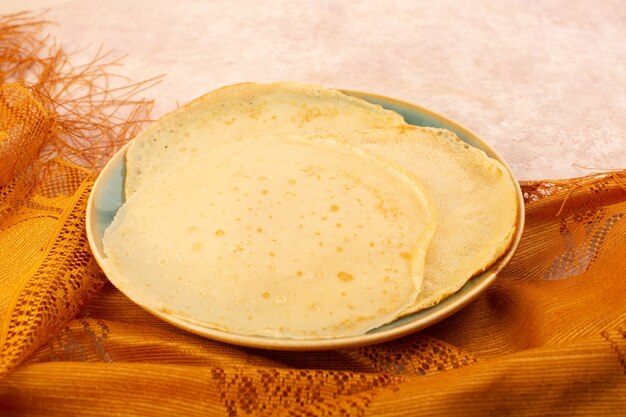 A top view delicious pancakes inside round plate on the pink desk food meal dessert pastry