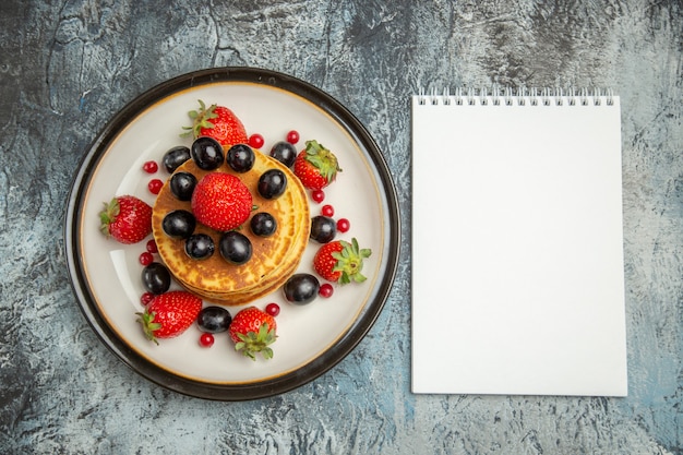 Top view delicious pancakes with fruits and berries on light surface dessert fruit cake