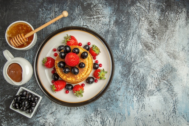 Top view delicious pancakes with honey and fruits on light surface fruit cake sweet