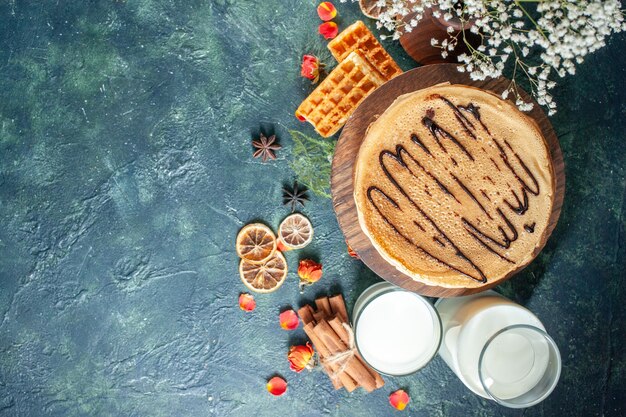 Вид сверху вкусные блины с молоком на темно-синей поверхности