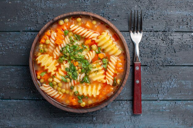 Top view delicious pasta soup from spiral italian pasta with greens on dark desk dinner dish italian pasta soup sauce