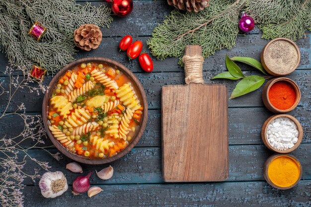 Top view delicious pasta soup from spiral italian pasta with seasonings on a dark-blue rustic desk cuisine soup pasta color dish