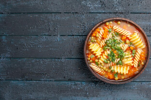 暗い机の上の皿の中に緑と野菜が入ったトップビューのおいしいパスタスープイタリアンパスタスープディナーソース