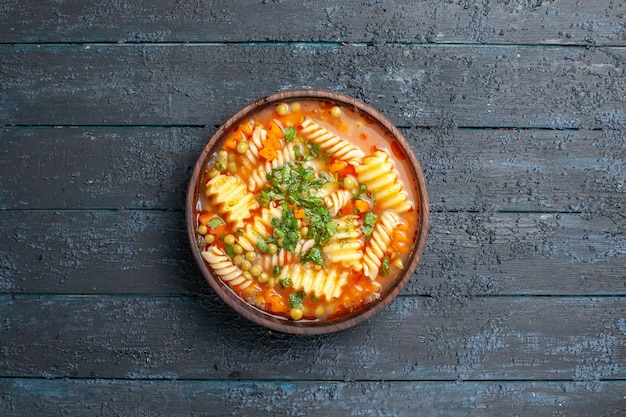 暗い机の上の皿の中に緑と野菜が入ったトップビューのおいしいパスタスープイタリアンパスタスープ食事ディナー