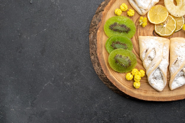 Top view delicious pastries with dried fruit slices on grey floor fruit dry raisin sweet cake