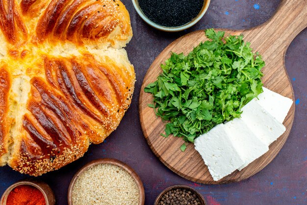 Top view delicious pastry with greens and white cheese on dark background.