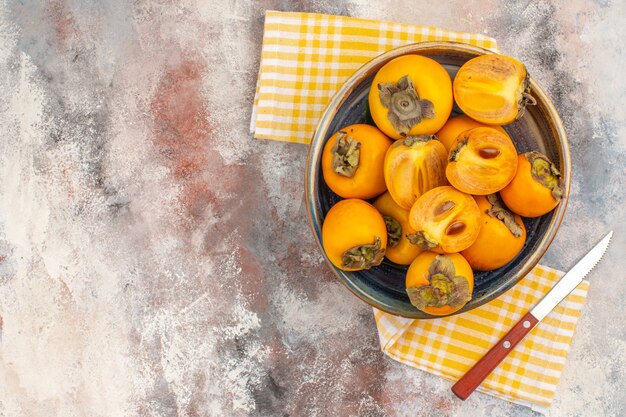 Top view delicious persimmons in a bowl on nude background