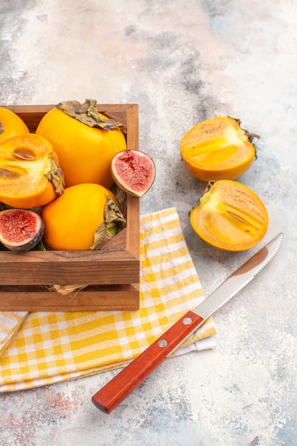 Top view delicious persimmons and cut figs in wood box on nude background