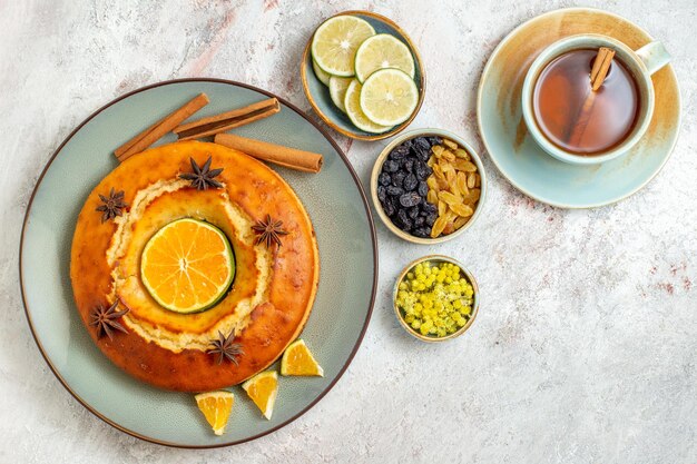 Top view delicious pie with cup of tea on the white background fruits sweet nut cake pie biscuit