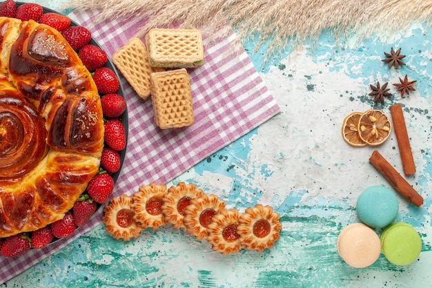 Top view delicious pie with red strawberries and waffles on the blue surface