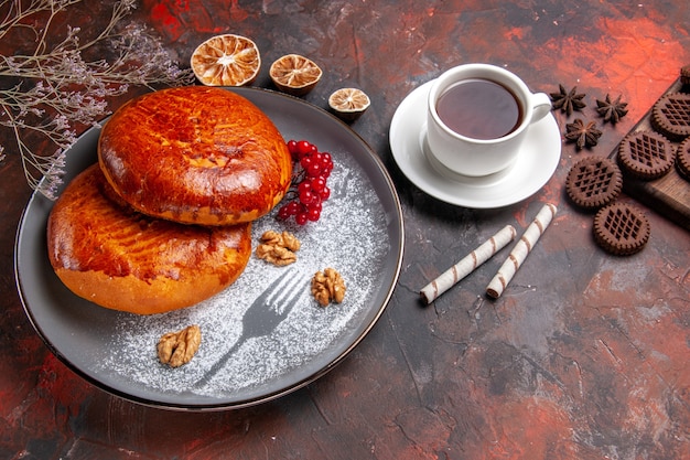 Vista dall'alto deliziose torte con una tazza di tè sulla pasticceria torta torta dolce scrivania scuro