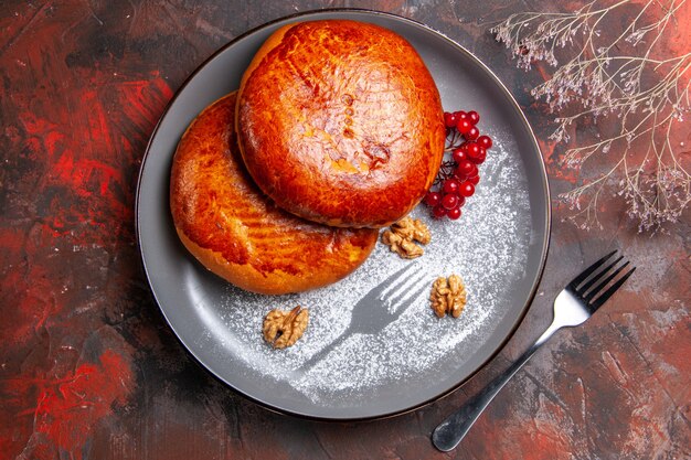 Top view delicious pies with red berries on dark table cake sweet pastry pie