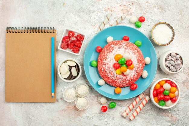 Top view delicious pink cake with colorful candies on white desk rainbow color dessert cake candy