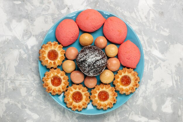 Top view delicious pink cakes with cookies and chocolate cake on white surface