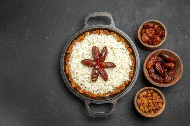 Vista dall'alto deliziosa farina di riso cotto plov con uvetta all'interno di una padella sulla superficie scura cibo cena orientale pasto