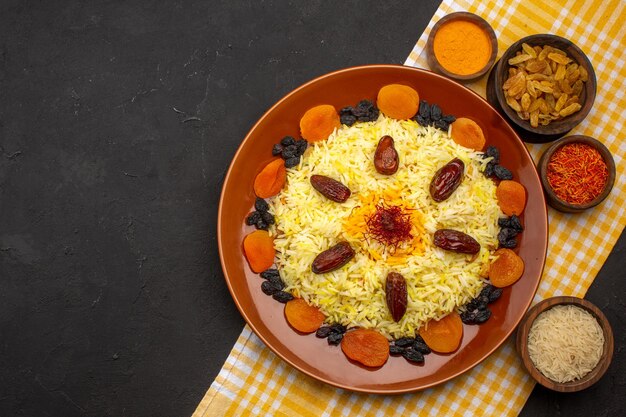 Top view delicious plov with different raisins on dark space