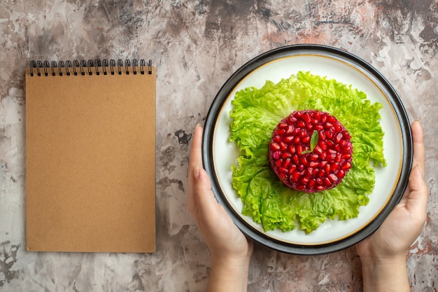 Top view delicious pomegranate salad round shaped on green salad on light background