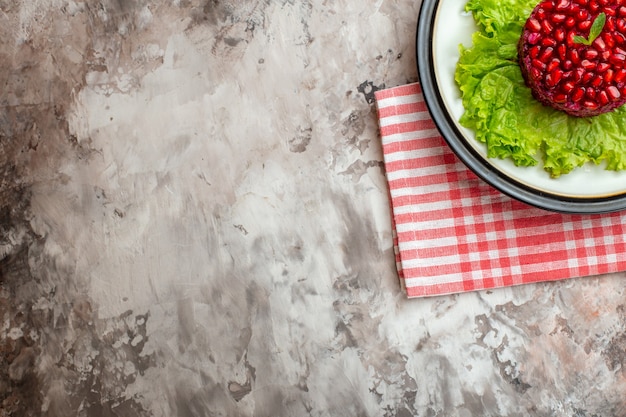 Top view delicious pomegranate salad round shaped on green salad on light background