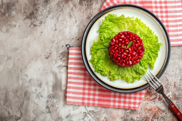 Free photo top view delicious pomegranate salad round shaped on green salad on light background