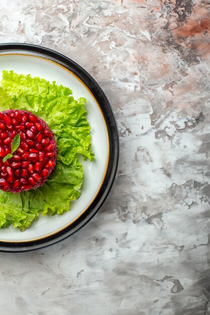 Top view delicious pomegranate salad round shaped on green salad on light background