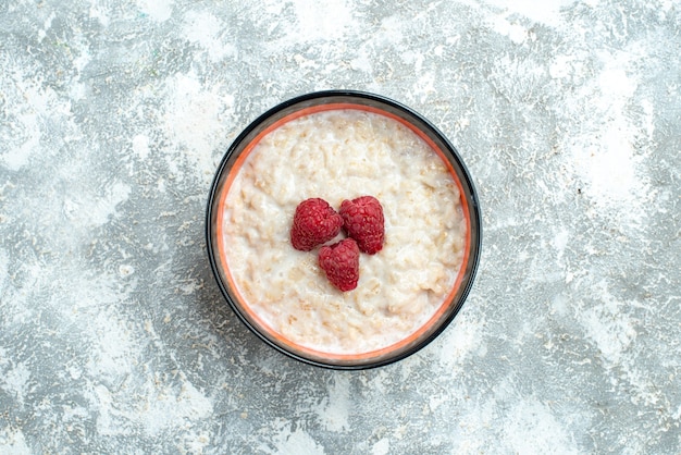 Top view delicious porridge with raspberries on a light background