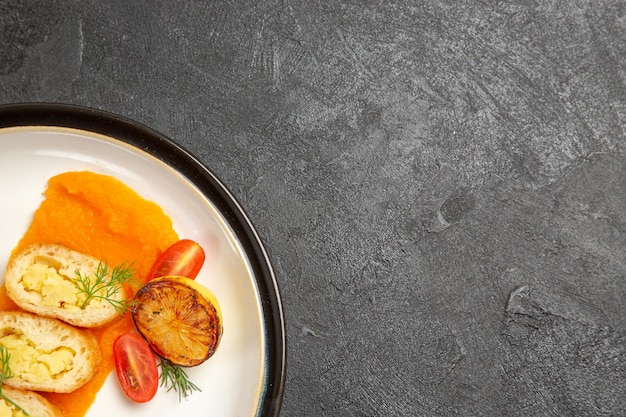 灰色の背景のオーブン焼き色皿ディナースライスのプレートの内側にカボチャが付いている上面図おいしいポテトパイ