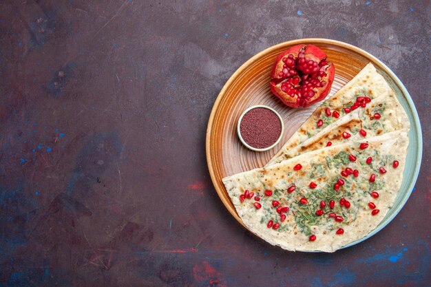 Top view delicious qutabs cooked dough pieces with greens and pomegranates on dark surface dough meal dinner cooking