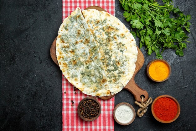 Top view delicious qutabs cooked dough slices with seasonings and greens on a grey space