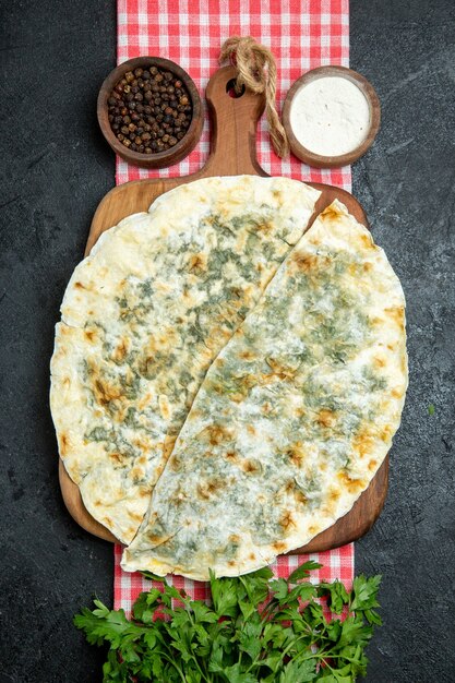 Top view delicious qutabs cooked dough slices with seasonings and greens on grey space