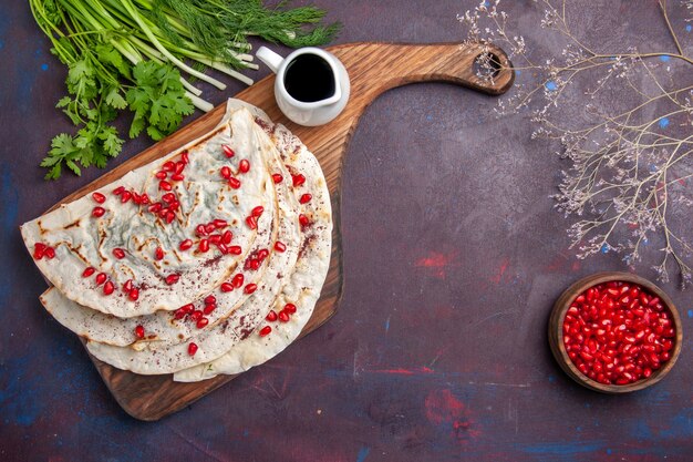 Top view delicious qutabs pitas with ground meat and fresh pomegranates on dark surface dough pita meat meal