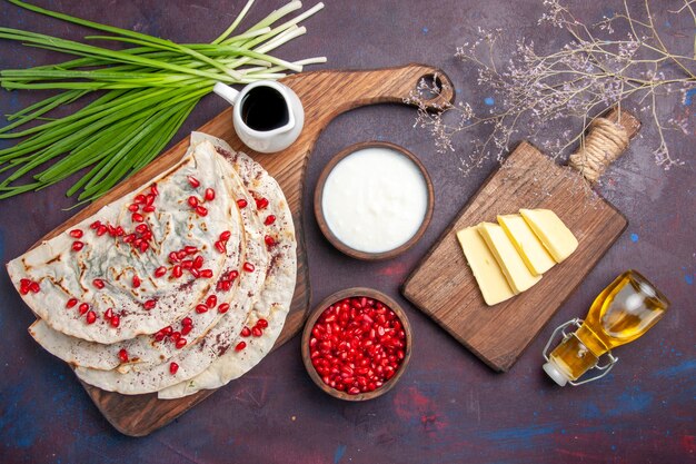 Top view delicious qutabs pitas with meat olive oil and fresh pomegranates on dark surface dough pita meat meal pastry food