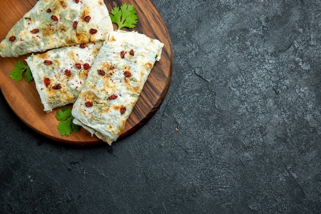 Foto gratuita vista dall'alto deliziosi qutab arrotolati verdi fette di pasta ripiene sullo spazio grigio