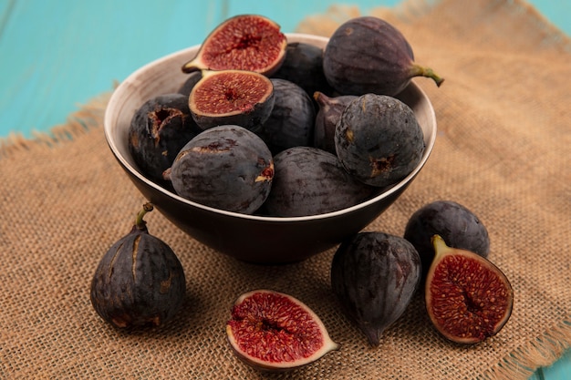 Top view of delicious ripe black mission figs on a bowl on a sack cloth on a blue wall