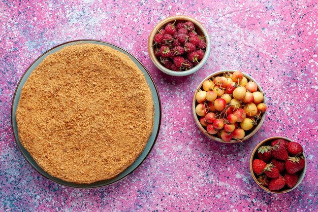 Foto gratuita vista dall'alto una deliziosa torta rotonda all'interno del piatto con frutta sulla torta da scrivania rosa brillante torta biscotto dolce cuocere lo zucchero